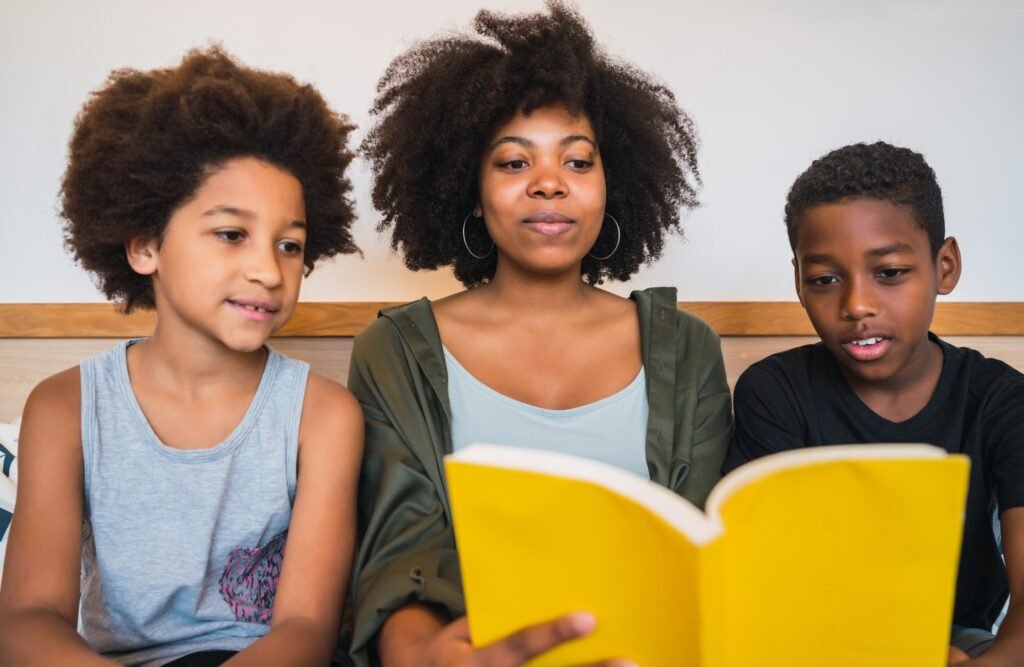 Afro mother reading a book to her children.